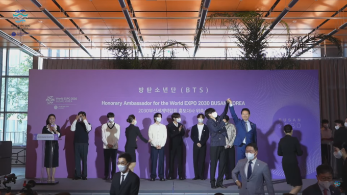 장성민 대통령실 정책조정기획관이 ‘2030 부산세계박람회 홍보대사 위촉식’에서 방탄소년단 뷔의 팔을 갑자기 들어 올리며 사진 촬영을 해 논란이 됐다. (사진=2030부산세계박람회 유치 공식 유튜브 채널 갈무리)
