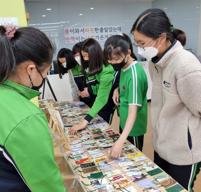  광동책숲 도서부가 지구의 날을 맞아 학생들에게 버려진 책 표지로 만든 책갈피를 나눠주고 있다. (사진=남양주광동중학교 제공)