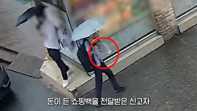 지난 6월 23일 보이스피싱 현금수거책으로부터 돈이 든 쇼핑백을 전달받은 40대 택배기사 A씨. (사진=경기남부경찰청 제공)