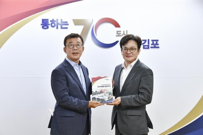 민선8기 김포시장직 인수위원회가 인수위 활동사항 전반을 담은 백서를 발간 홍철호 인수위원장(왼쪽)이 김병수 시장에게 전달하고 있다. (사진=시장직인수위원회 제공)