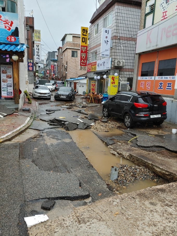 군포시 산본1동 차이나타운 거리가 집중 호우로 인해 차량들이 뒤엉키고 도로가 파손되 아스팔트가 뒤집혀 있는 현장. (사진= 산본 1동 주민 제보)