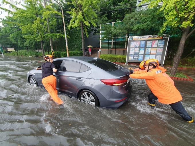 지난 8일 인천 미추홀구 용현동에서 폭우로 도로에 고립된 자동차를 소방대원들이 밀고 있다. ( 사진 = 인천소방본부 제공 )