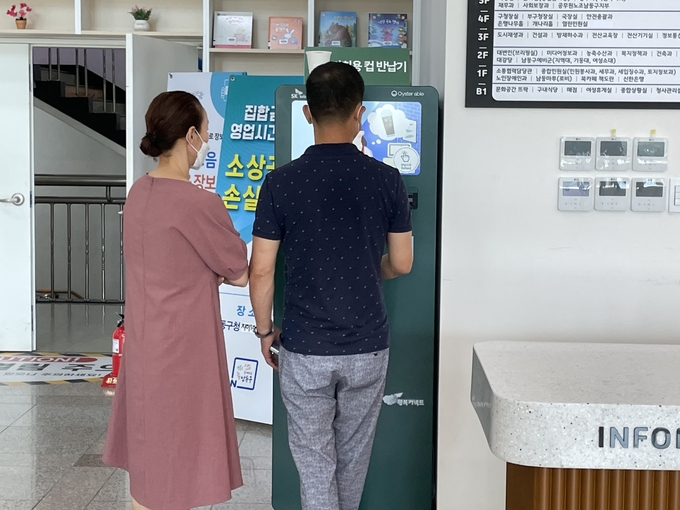 18일 오후 인천 남동구청 1층에 설치된 다회용컵 반납기 앞에서 시민들이 보증금을 돌려 받기 위해 컵을 넣고 있다. ( 사진 = 조경욱 기자 )