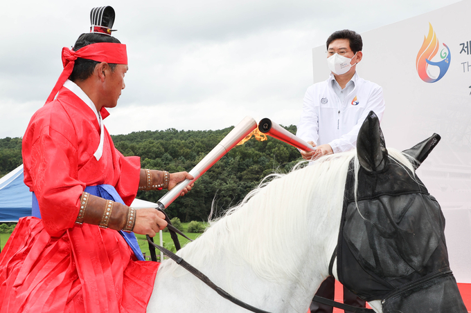 제68회 경기도체육대회 성화채화식에서 이상일 용인특례시장이 승전장 복식을 한 첫 주자에게 성화를 전하고 있다(사진=용인시 제공)