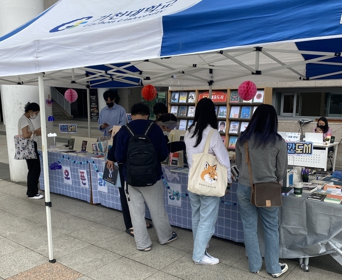 가천대 중앙도서관이 도서접근성을 높이기 위해 대학 프리덤광장에서 운영하고 있는 오픈라이브러리에서 학생들이 책을 빌리고 있다. (사진=가천대 제공)