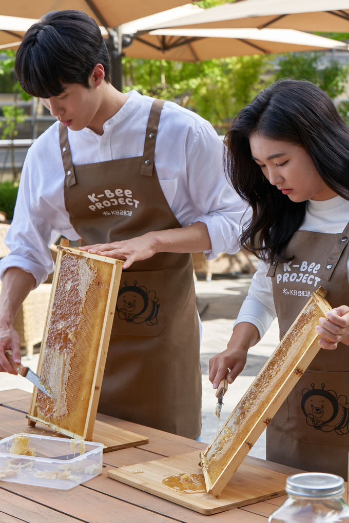 KB금융 황선우 선수와 이예원 선수가 KB국민은행 본점 옥상에 조성된 ‘K-Bee 도시양봉장’에서 올해 첫번째 꿀 수확 행사를 가졌다. (사진=KB금융그룹 제공)