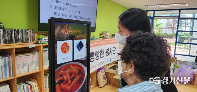 빵빵한 봉사단 청소년이 한 할머니의 손을 잡고 키오스크 사용법을 설명하고 있다. (사진=포천시 제공)
