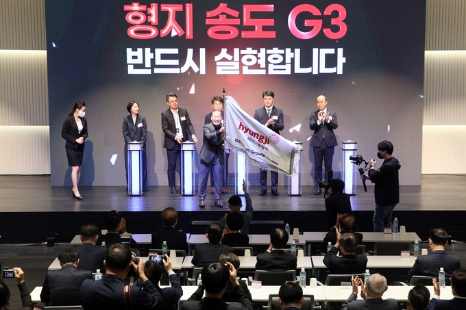 21일 인천 송도국제도시 형지 글로벌 패션복합센터에서 열린 입주 기념행사에서 최병오 형지그룹 회장(가운데)이 깃발을 들고 기념촬영을 하고 있다. ( 사진 = 인천경제청 제공 )