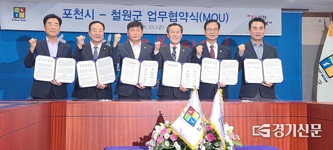 협약서와 공동결의문에 서명한 6명의 주요 인사가 협약서와 공동결의문을 들어보이고 있다. 왼쪽부터 이현종 철원군수, 한기호 국회의원, 박기준 철원군의회 의장, 서과석 포천시의회 의장, 최춘식 국회의원, 백영현 포천시장. (사진=문석완 기자)