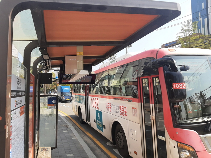  목재 그늘막, 난방기, 송풍기가 설치된 버스 정류소