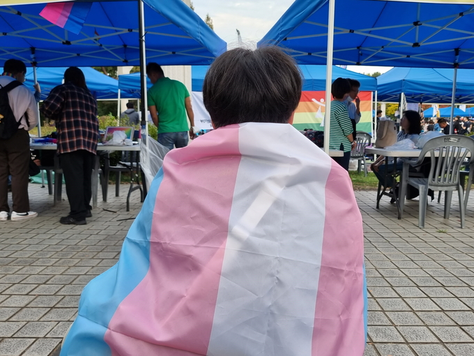 15일 오후 인천 퀴어축제에서 트랜스젠더 프라이드 플래그를 두른 참여자가 휴식을 취하고 있다. ( 사진 = 김민지 기자 )
