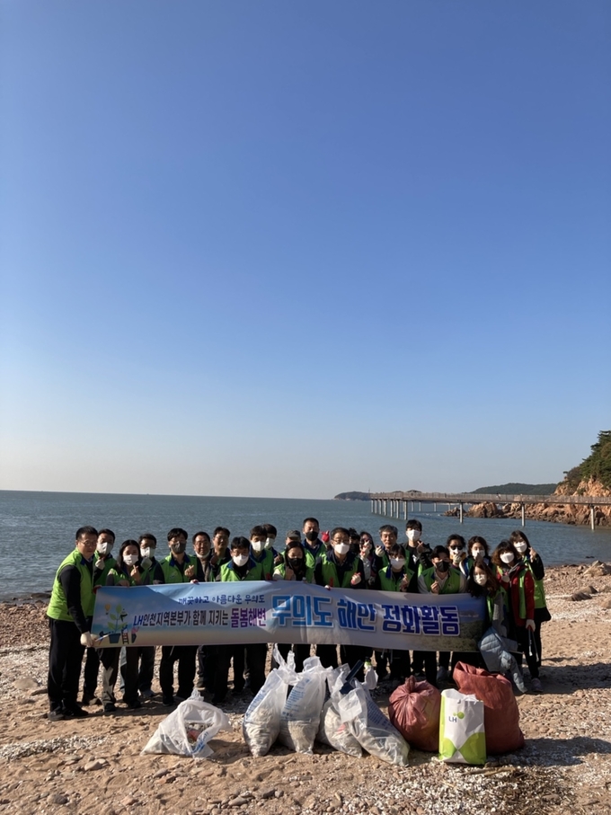 한국토지주택공사(LH) 인천지역본부 임직원 20여 명이 25일 중구 무의도 해안탐방로 인근 해안에서 해변 환경정화 활동을 한 뒤 기념촬영을 하고 있다. ( 사진 = LH 인천지역본부 제공 )