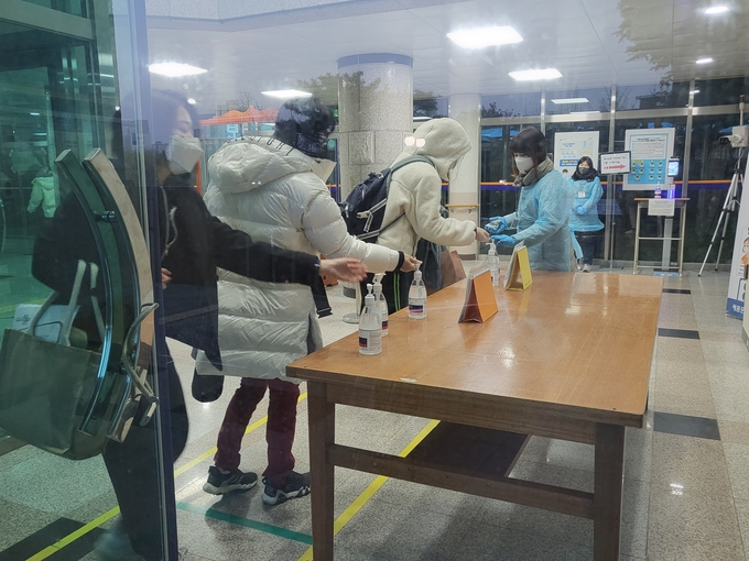 17일 오전 수원 돌마고에서 방역 요원의 안내에 따라 수험생들이 입실 전 손 소독을 하고 있다. (사진=정해림 기자)