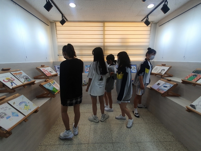  한빛중 예술공감터에서 열린 2022 책표지그림대회 수상작을 구경한는 학생들. (사진=파주한빛중학교 제공)