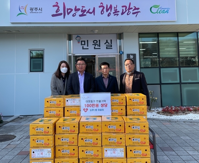 광주시 능평2통 마을주민들이 어려운 이웃에게 전달해 달라며 박진호 동장에게 귤 박스를 기탁하고 있다 (사진=광주시 제공)