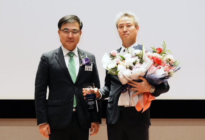 탁현수 한난 부사장(사진 오른쪽)이 수상 후 손병두 증권거래소 이사장과 기념촬영을 하고 있다. (사진=한국지역난방공사 제공)