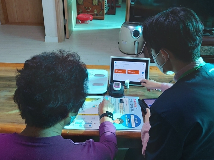 ‘AI·IoT기반 어르신 건강관리 사업’ 참여자가 스마트기기에 대한 설명을 듣고 있다. ( 사진 = 옹진군 제공 )