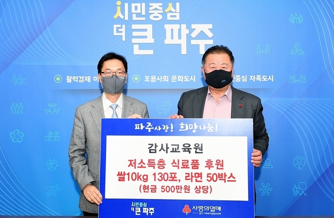  조성은 감사교육원장(좌측)이 김경일 파주시장에게 이웃돕기 물품을 전달하고 있다.(사진=파주시 제공)
