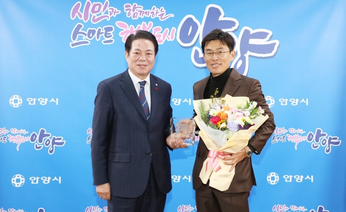 프로축구 K리그2 FC안양의 구단주인 최대호 안양시장(왼쪽)이 4년 간 팀을 이끌어온 장철혁 단장에게 공로패와 꽃다발을 전달한 뒤 기념사진을 찍고 있다. (사진=FC안양 제공)