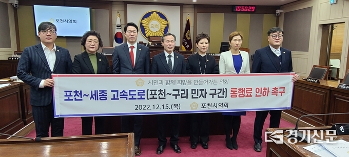 포천시의회 의원 전원이 포천-세종 고속도록 통행료 인하를 촉구하는 현수막 앞에서 기념촬영하고 있다. (사진=문석완 기자)
