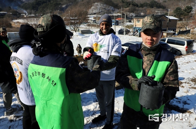 한미 양국 장병들이 인간띠를 만들어 손수레에서 연탄을 옮기고 있다. (사진=제5포병여단 제공)
