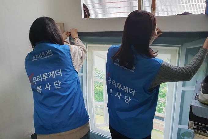 우리금융미래재단 직원들이 쪽방촌 주민들을 위해 방한커튼을 설치하고 있다. (사진=우리금융미래재단 제공)