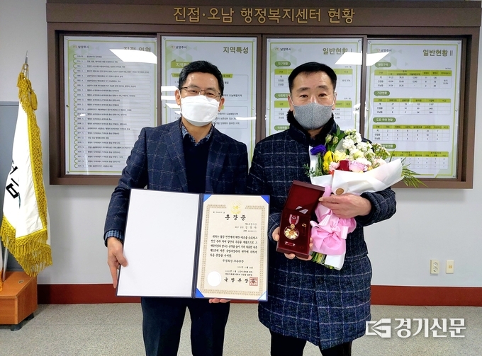 6·25전쟁 당시 공적을 인정받아 결정된 무공훈장을 받지 못하고 72년 후인 지난 26일 유족인 김성국씨(사진 오른쪽)에게 진접오남행정복지센터 윤경배 센터장이 훈장을 전달하고 기념촬영을 하고 있다.(사진=남양주시 제공)
