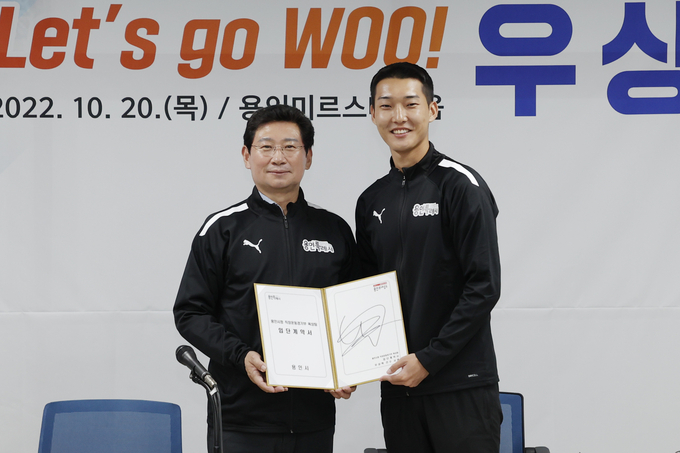우상혁(오른쪽)이 지난해 10월 20일 용인 미르스타디움에서 열린 '용인시청 직장운동경기부 육상팀 입단식'에서 계약서에 사인한 뒤, 이상일 용인시장과 기념 촬영하고 있다.(사진=용인시 제공)