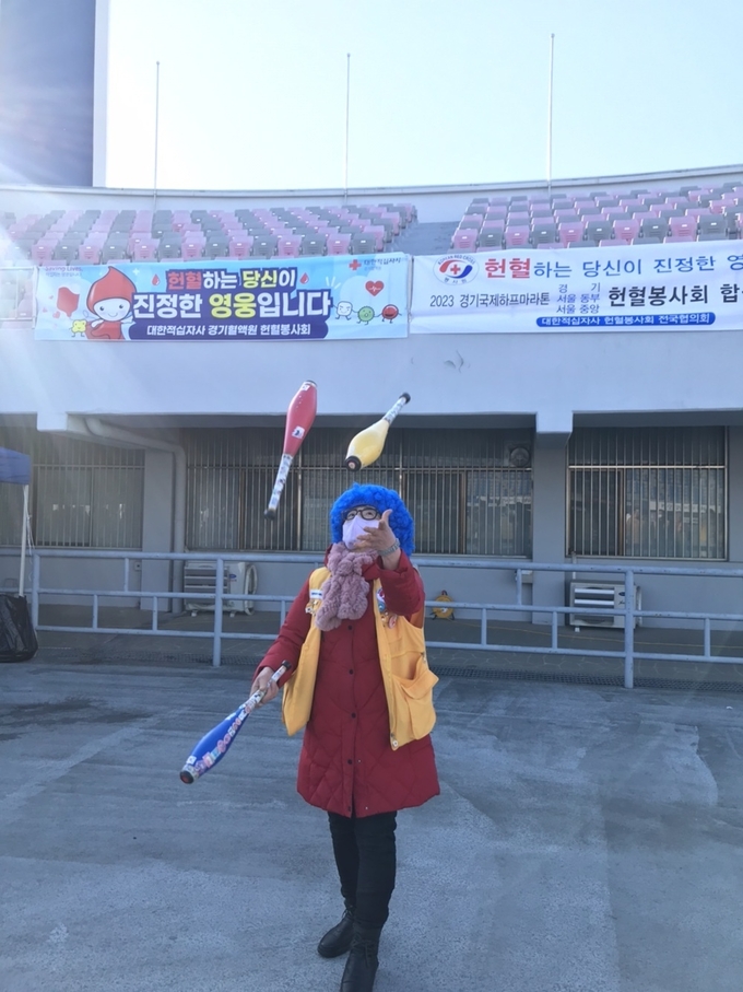 2023 경기국제하프마라톤대회가 열린 수원종합운동장에서 최성자 서울중앙혈액원 나누미봉사회 부회장이 삐에로 분장을 하고 저글링을 선보이고 있다. (사진=마라톤 특별취재팀)