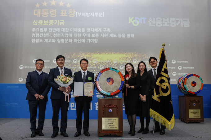 김충배 신용보증기금 전무이사(왼쪽에서 세번째)가 27일 '제11회 국민권익의 날 기념식'에서 부패방지분야 종합청렴도 평가 유공 대통령 표창을 받은 후 직원들과 기념촬영을 하고 있다. (사진=신용보증기금 제공)