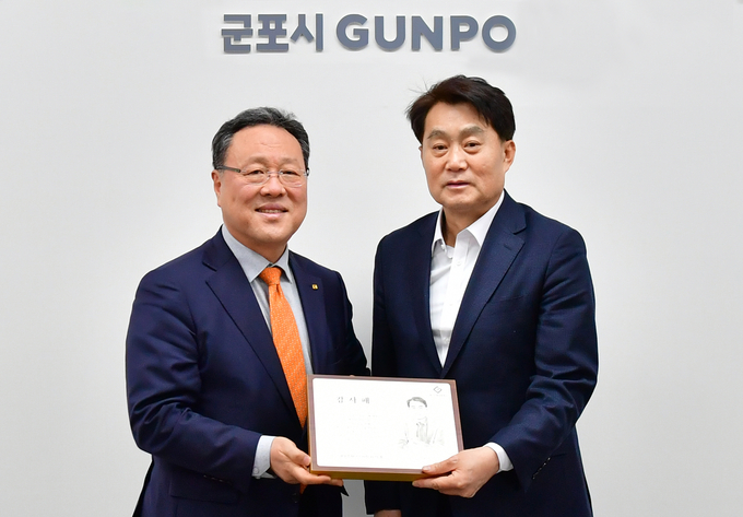시석중 경기신용보증재단 이사장(왼쪽)이 하은호 군포시장에게 감사패를 전달하고 기념촬영을 하고 있다. (사진=경기신보 제공)