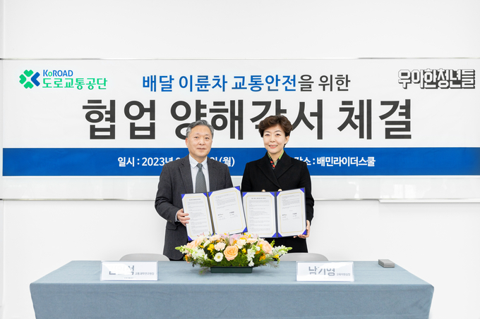 남기영 우아한청년들 교육지원실장(오른쪽)과 김인석 도로교통공단 교통과학연구원장이 지난 13일 경기도 남양주시에 위치한 배민라이더스쿨에서 ‘배달 이륜차 교통안전을 위한 양해각서’를 체결한 후 기념 촬영을 하고 있다. (사진=우아한형제들 제공)