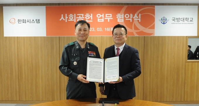 어성철 한화시스템 대표이사(오른쪽)와 김홍석 국방대학교 총장이 사회공헌을 위한 업무협약을 맺은 뒤 기념 촬영을 하고 있다. (사진=한화시스템)