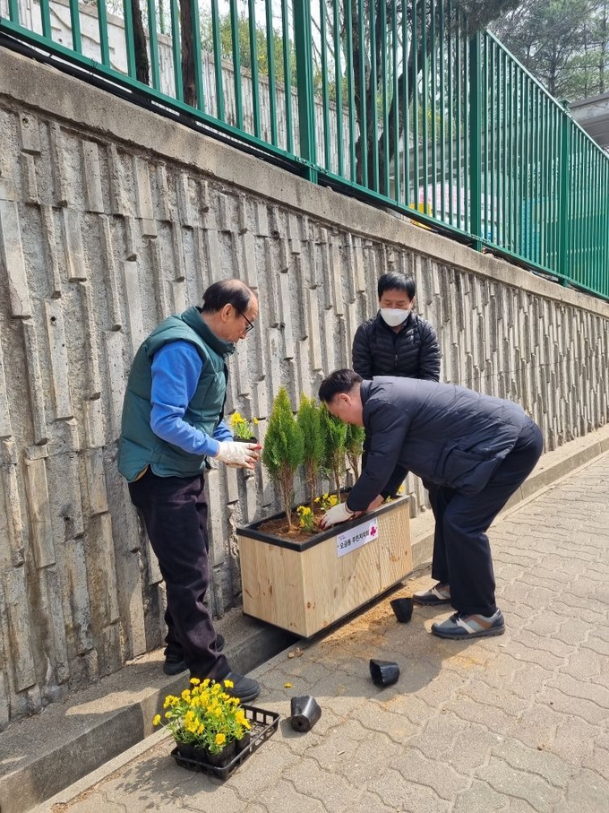 군포시 오금동 주민자치회가 오금초교길에 꽃길을 조성하고 있다.(사진=군포시 오금동 주민자치회 제공)