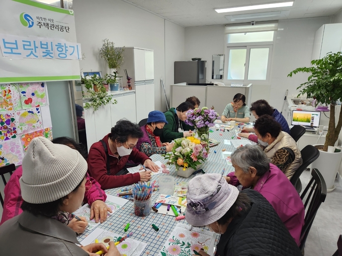 산본주몽1단지 노인들이 꽃과 함께 예쁜 스토리 컬러링에 그림을 그리고 있다. (사진 = 산본주몽1단지 제공)
