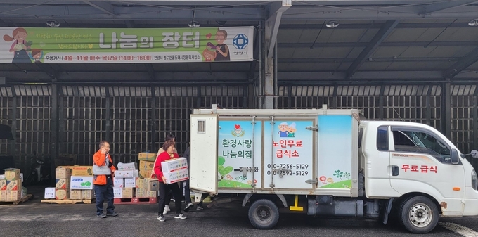 안양시농수산물도매시장관리사업소 나눔의 장터에서 지역 복지시설 관계자가 상인들이 기탁한 식자재를 차에 싣고 있다.(사진=안양시 제공) 
