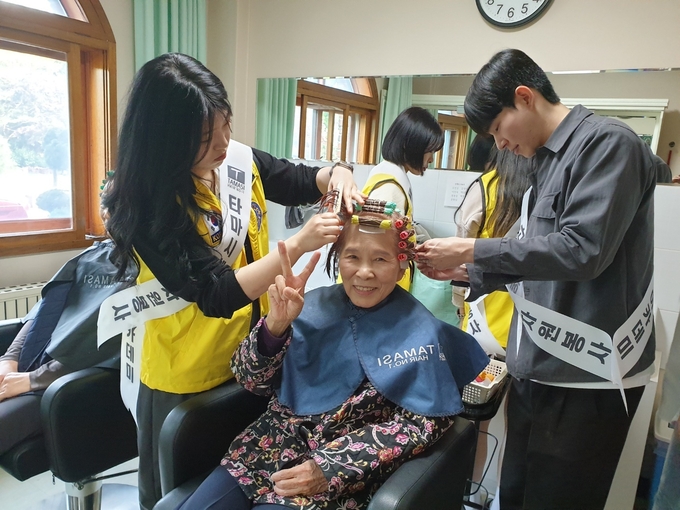 평화의 모후원에서 이명자 씨가 봉사자들에게 파마를 받으며 기념 촬영을 하고 있다. (사진=나규항 기자)
