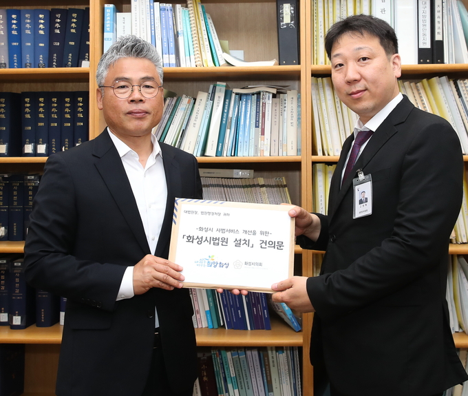  박형일(사진 왼쪽) 화성시 자치행정국장이 법원행정처 고원혁 기획운영담당관에게 법원 설치 건의문을 전달하고 있다.(사진/화성시제공)