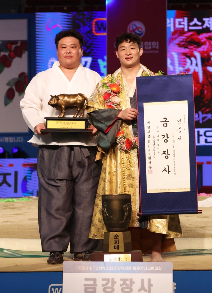 21일 충북 보은군 보은군민체육센터에서 열린 ‘위더스제약 2023 민속씨름 보은장사씨름대회’ 사흘째 금강급(90㎏급) 장사결정전(5판 3선승제)에서 우승한 김기수(오른쪽·수원특례시청)가 이충엽 수원특례시청 감독(왼쪽)과 기념사진을 찍고 있다. (사진=대한씨름협회 제공)