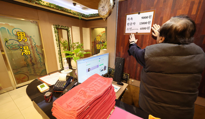 한 업주가 인상된 요금표를 만지고 있다. (사진=연합뉴스 제공)