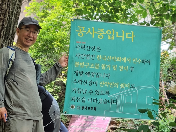 한국산악회 변기태 회장이 기자의 요청으로 '공사입니다' 라는 안내문 걸개 앞에 섰다. 변 회장은 많은 폐건자재 등을 운반하다가 심한 심장 통증이 수반되는 부정맥 증상으로 3일간 입원 치료를 받기도 했다.(사진=이화우 기자)