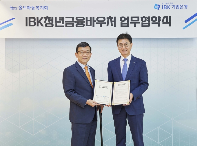 박청준 기업은행 개인고객‧카드사업그룹장(오른쪽)이 지난 27일 협약식을 마치고 김정오 홀트아동복지회이사장과 기념촬영을 하고 있다. (사진=IBK기업은행 제공)