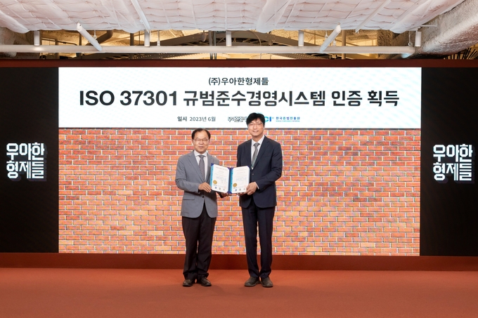 우아한형제들 함윤식 고객중심경영부문장(오른쪽)이 한국준법진흥원 황인학 원장으로부터 ISO37301 인증서를 수여받았다. (사진=우아한형제들 제공)