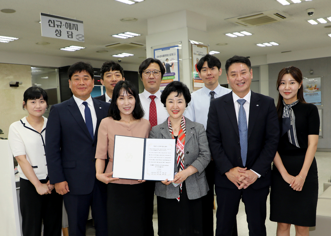 강신숙 Sh수협은행장(앞줄 오른쪽 3번째)이 신입 행원 시절을 보낸 전주지점의 직원들로부터 ‘마부작침(磨斧作針) 결의문’을 전달받고 기념촬영을 하고 있다. (사진=Sh수협은행 제공)