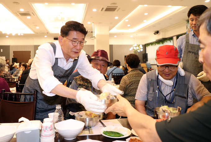 12일 수원 디에스컨벤션에서 열린 삼계탕 나눔 데이에서 김기정 수원시의회 의장이 삼계탕을 배식하고 있다. (사진=수원시의회 제공)