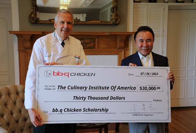 제너시스BBQ 그룹 윤홍근 회장(오른쪽)이 세계 3대 요리학교인 CIA(The Culinary Institute of America) hydepark 캠퍼스(뉴욕주)에 방문해 미래 외식산업 리더 양성을 위한 장학금 3만 달러를 마크 에릭슨 총장에게 전달하고 있다. (사진=제너시스BBQ 제공)
