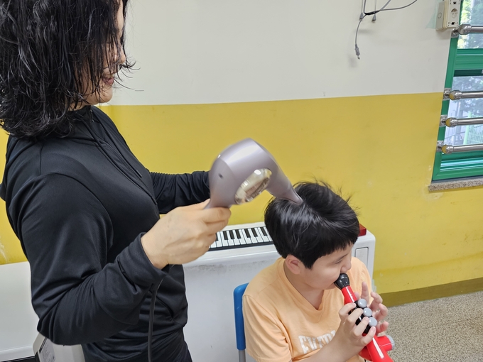 이정애 특수교육지도사가 한 학생의 머리를 말려주고 있다. (사진=수원서광학교 제공)