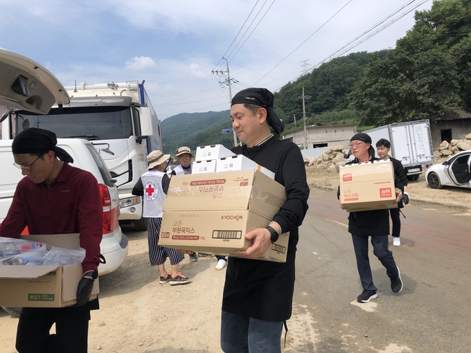 교촌에프앤비 임직원 봉사단과 교촌치킨 가맹점주들이 경북 예천군 감천면 수해현장에 방문해 치킨 나눔 활동을 진행하고 있다. (사진=교촌에프앤비 제공)