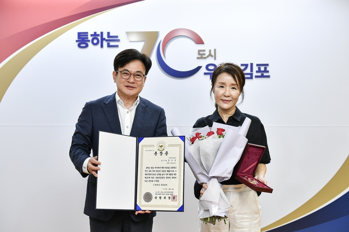 김병수 김포시장(좌)과 참전유공자 故한인석 선생 자녀 한희숙 씨가 화랑무공훈장을 들고 함께 기념사진을 촬영하고 있다. (사진=김포시 제공)