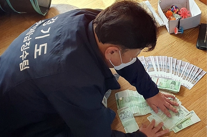 경기도 관계자가 고액체납자에 대한 가택 수색을 통해 압류한 현금을 정리하고 있다. (사진=경기도 제공)